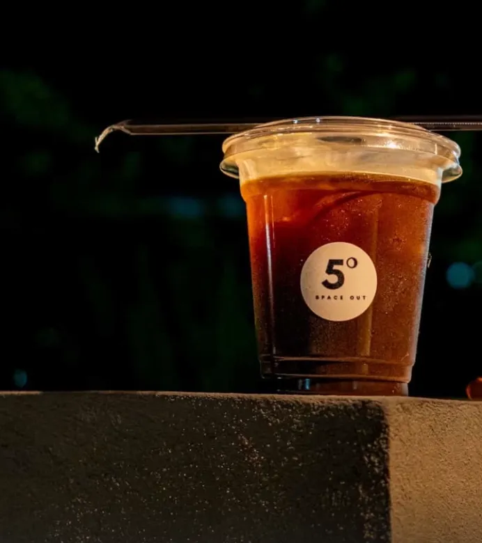 Iced drink lit up against the dark, marked with the 5° Space Out sticker